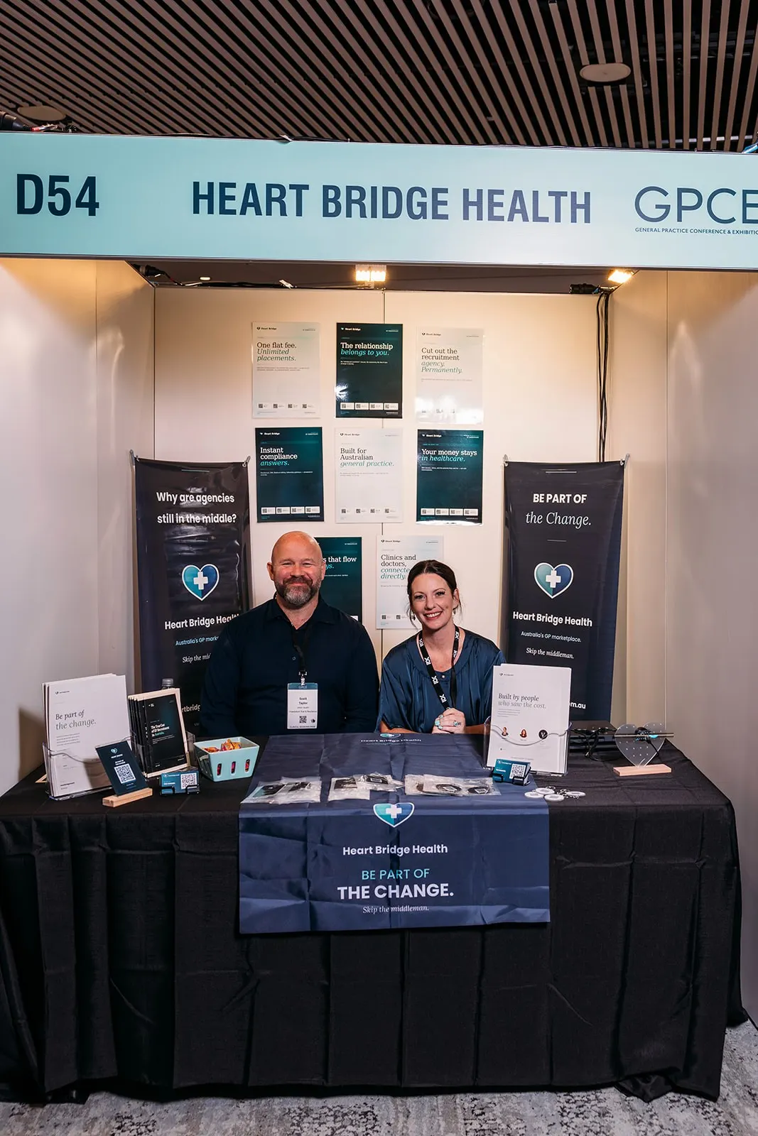 Two Heart Bridge Health team members seated behind the stand desk at GPCE