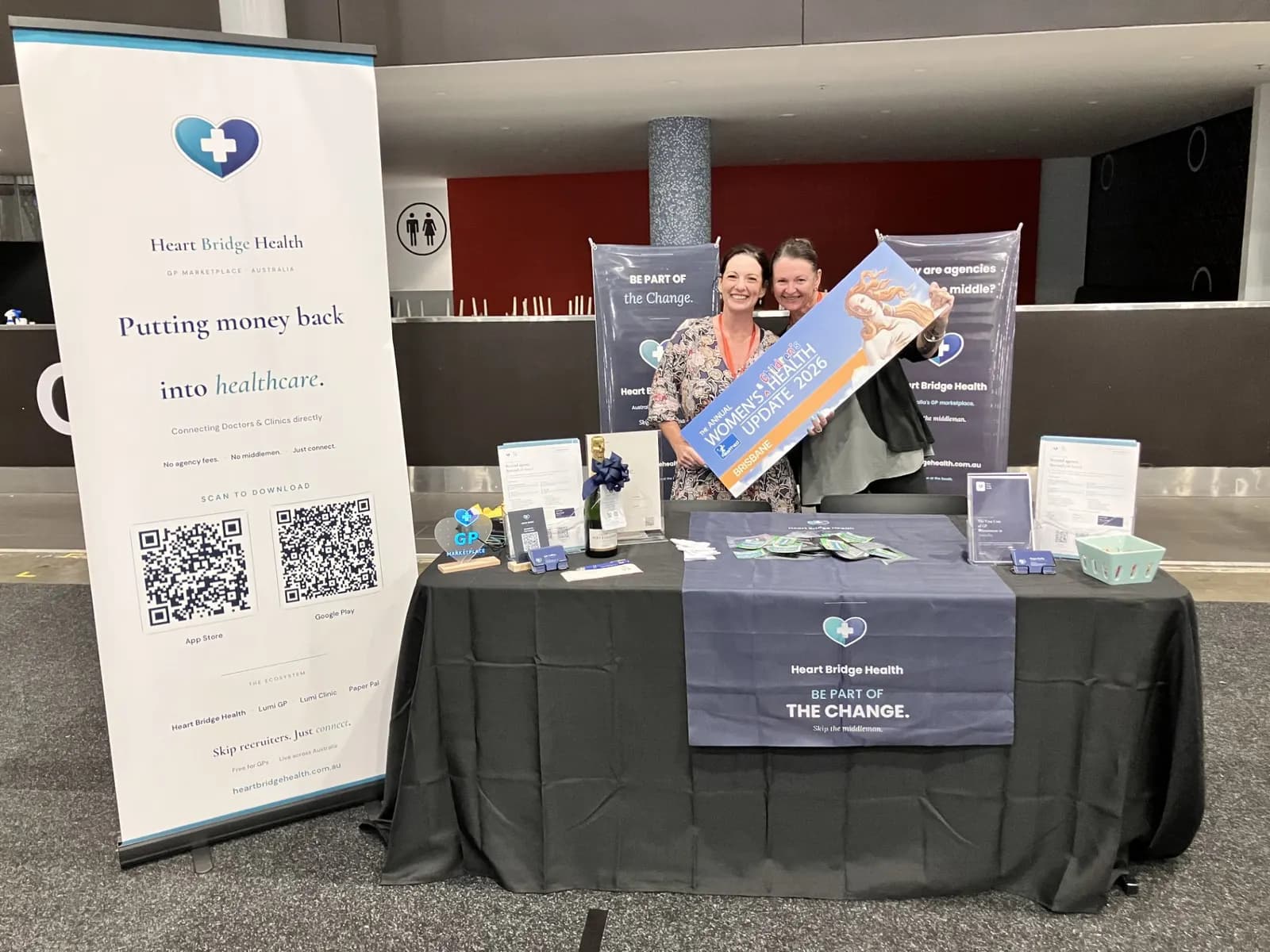 The Heart Bridge Health stand set up at a HealthEd event with pull-up banner and QR code